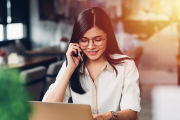 Freelance working woman with laptop computer, he calling smartphone talking with customer in coffee shop