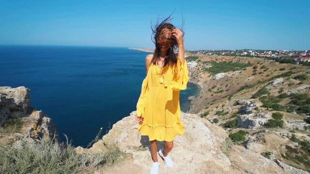 closeup clow motion portrait beautiful young smiling brunette woman with long wind blowing hair. girl wearing in orange sundress and sunglasses, wind flying hair to camera
