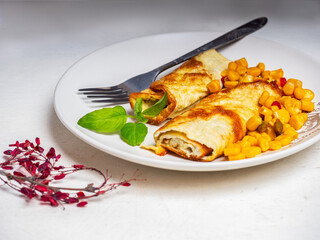 Omelet and canned vegetables on a light plate standing on a white table with a fork