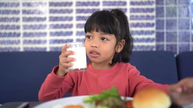 Asian child girl drinking a glass of milk.