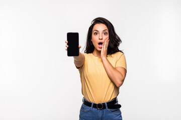 Fototapeta premium Beautiful woman looking camera with opened mouth and showing smartphone with blank screen isolated on white background