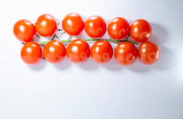 Branch of cherry tomatoes on a light background, copy space