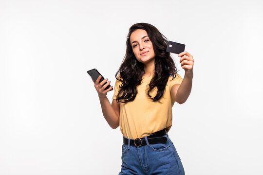 Image of a beautiful young excited pretty woman using mobile phone holding credit card posing isolated over white background