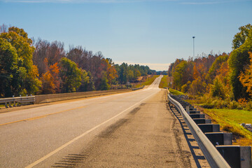 Fototapeta premium Road in the country with beautiful Fall colors and distant traffic