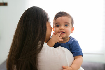 Baby boy teething and hugging mom