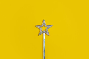 Magic wand with star shape in the center of yellow background with copy space. Minimalistic banner with colors of the year 2021 - Illuminating and Ultimate Gray. - 398375504