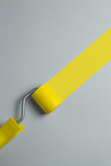 Paint roller painting diagonal yellow stripe on a gray background. Minimalistic banner with colors of the year 2021 - Illuminating and Ultimate Gray. - 398375554