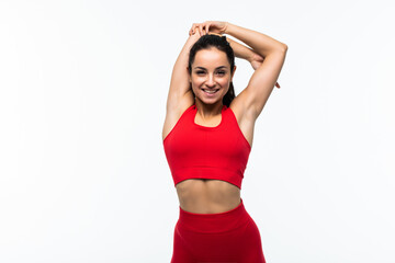 Portrait of happy young woman with arms raised doing stretching exercise against white background