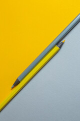 Gray and yellow pencils on a two-color background lying parallel in opposition to each other. Minimalistic banner with colors of the year 2021 - Illuminating and Ultimate Gray. - 398375714
