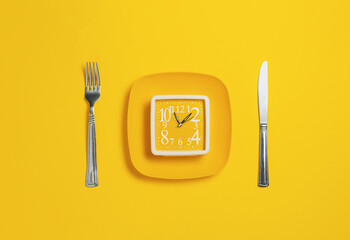Clock on a plate with cutlery on a yellow background. Lack of time concept. Minimalistic banner with colors of the year 2021 - Illuminating and Ultimate Gray - 398375766