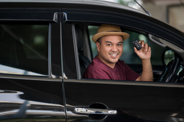 Young handsome asian man getting the new car.He showing car key and very happy. Buy or rent a car concept.