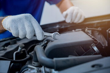 Auto mechanic holding wrench prepair to car service care. Car open the bonnet to checking engine and service.