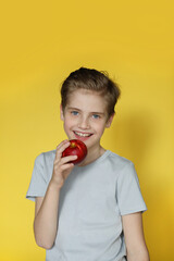 Cute boy laughs and eats an apple