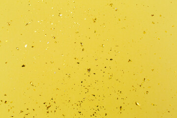 Gold confetti on yellow paper background. Festive holiday backdrop. Birthday congratulations Christmas New Year. Flat lay, top view, copy space.