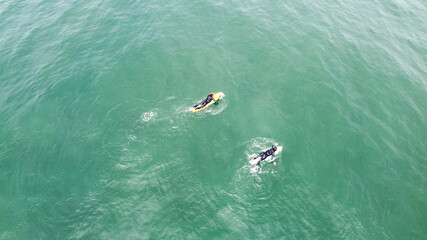 Two surfers sails on a surfboards in a calm ocean, top view