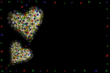 Two hearts made of colored artificial stones on black background. Christmas. Poem background. Valentine's Day. Copy space.