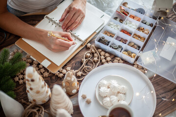 Top view of young woman is writing goals for New Year 2021 on diary on desk with Christmas Tree
