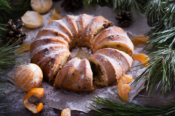 Obraz na płótnie Canvas Homemade delicious christmas or new year cake with tangerines on a wooden background with coniferous branches
