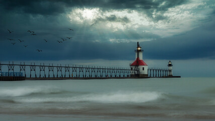 Long exposure photo of the St Joseph Michigan North Pier Lighthouses and Lake Michigan on a cloudy day with sun rays shining through