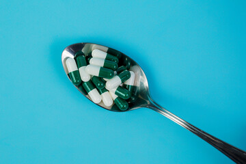 Pills in the Spoon on the Blue Background. Closeup. Space for text. Pharmacology and medicine struggle for health.Treatment and prevention of viral diseases. Medicine and health concept