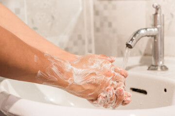 Close-up of man washing his hands in the bathroom. Hygiene concept for prevention COVID - 19.