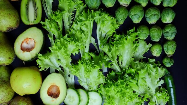 raw green vegetables, brussels sprouts. avocado, olives, fruits on black isolated background with place for text, concept of cooking appetizing homemade food, healthy food