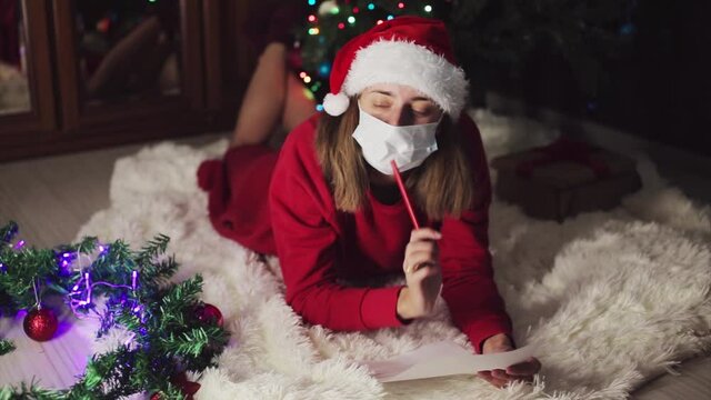 a woman in red clothes is sitting waiting for the new year. the concept of celebrating Christmas at midnight. holiday costume. a girl writes a letter to Santa Claus. wish list