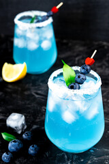  Cocktail with ice, blue curacao and blueberries on a black background for valentine's day