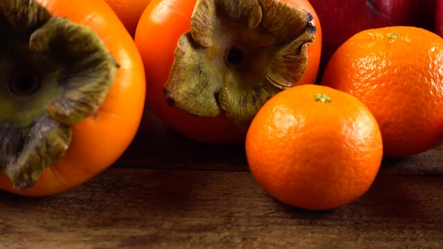 Tangerines, lemons, persimmons, oranges, apple and pomegranates on an old wooden vintage board.