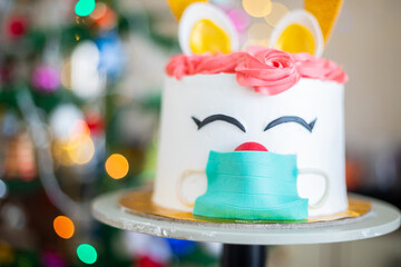 Christmas cake, deer wearing mask design, celebration during covid pandemic concept, blur bokeh background, selective focus, holiday and festive season. 