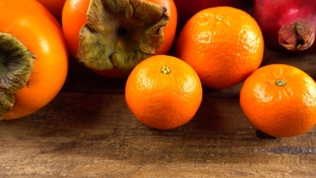Tangerines, lemons, persimmons, oranges, apple and pomegranates on an old wooden vintage board.