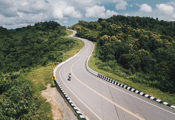 Aerial view of tourist riding a motorcycle on beautiful steep curved road (look like number 3) on the high mountain in Nan province, Thailand.