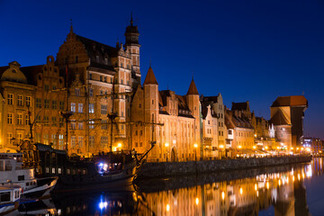 Fototapeta na wymiar Night view of lighted Motlawa embankment in Polish city of Gdansk .