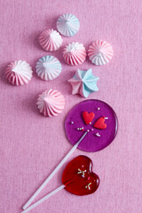 heart shaped lollipops and marshmallows on pink background, vertical