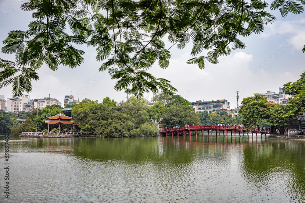 Wall mural Hanoi Vietnam August 18th 2018 : Tourists and locals crossing the Huc bridge, a landmark red wooden bridge leading over Hoan Kiem lake to a shrine