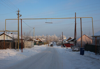 Fototapeta na wymiar Russia, Novosibirsk, 30.11.2020: street in the village in winter in a Siberian village with houses residents in the snow on the road