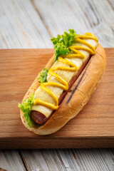 Closeup on cheese hot dog with mustard on the wooden board