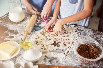 Kids covered in flour making cookie shapes out of dough