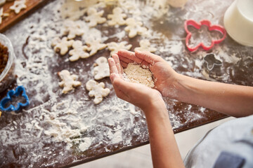 Two hands putting some flour on table with cookies