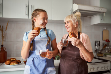 Lovely grandmother tasting pastries made together with her granddaughter