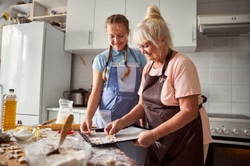 Happy teenage girl helping her grandma in the kitchen