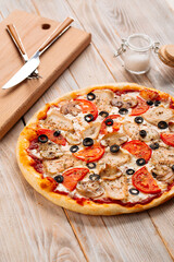 Closeup on chicken pizza with mushrooms and olives on the wooden table