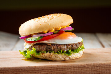 Side view on classic burger with egg on the wooden board