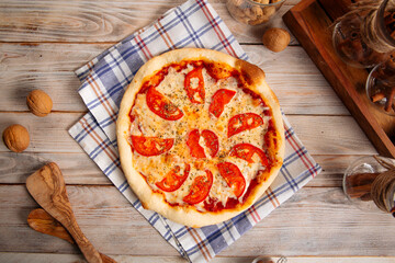 Top view on margherita pizza with tomatoes on the wooden background
