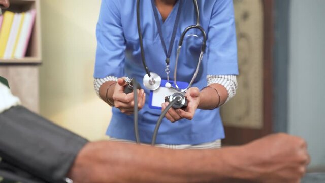 Unrecognizable doctor or nurse checking blood pressure or BP of patient at home.