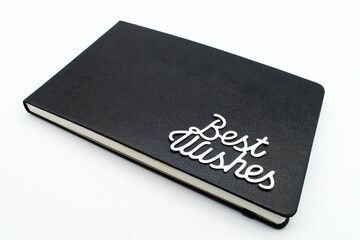 Black leather notebook with best wishes text on the cover 	