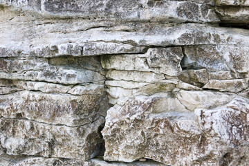 mountain textures of stones with interlayers of gypsum, colored quartz, clay, sand and other layers of various ores, with different textures, color and density, in gypsum ore quarry.