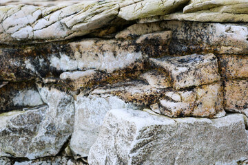 mountain textures of stones with interlayers of gypsum, colored quartz, clay, sand and other layers of various ores, with different textures, color and density, in gypsum ore quarry.