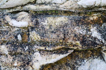 mountain textures of stones with interlayers of gypsum, colored quartz, clay, sand and other layers of various ores, with different textures, color and density, in gypsum ore quarry.