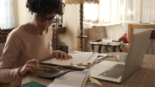 Home office working environment. Using laptop and working efficiently. Using technology and working at home productively. Young female adult study focused.